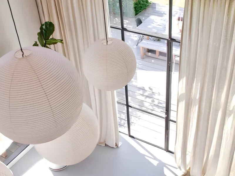 Crème linnen gordijnen in een lichte ruimte met papieren hanglampen