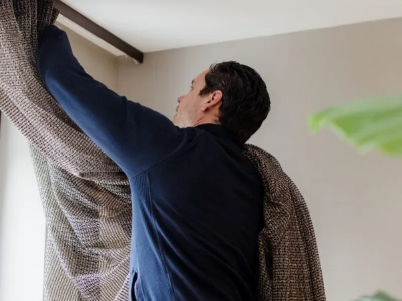 Monteur van AC Mooi Wonen hangt een gordijnrail op